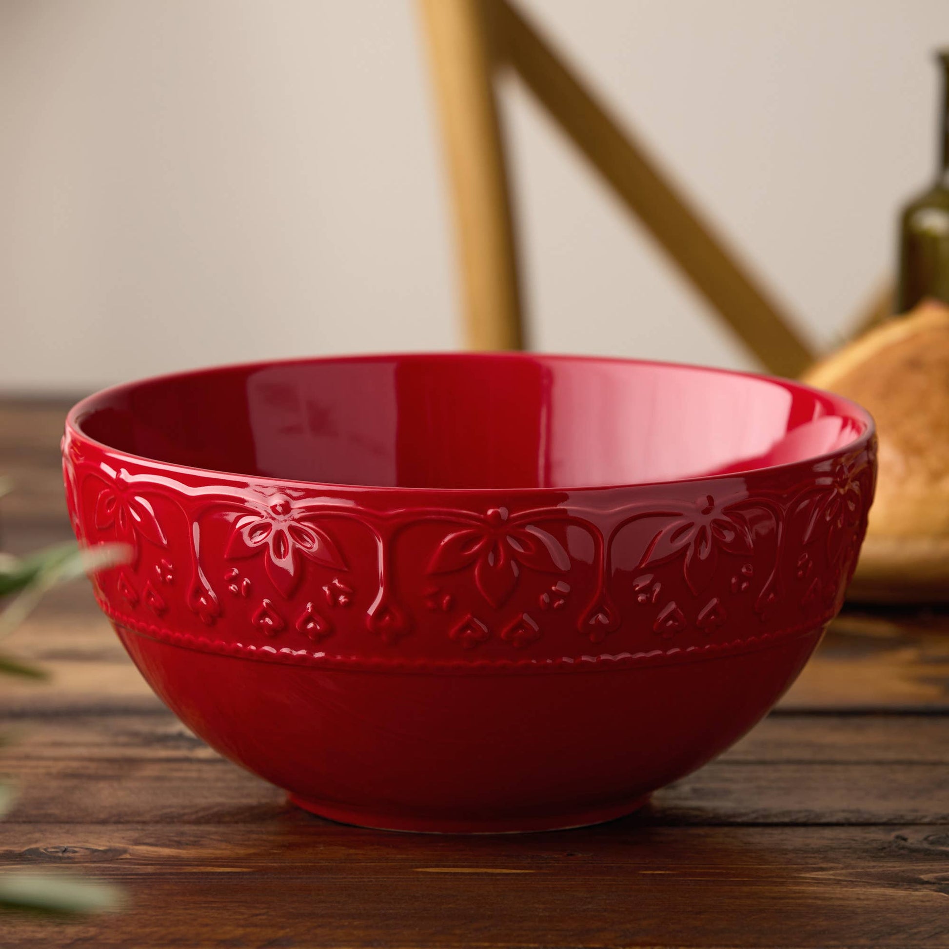 Red ceramic bowl with floral patterns on a wooden surface