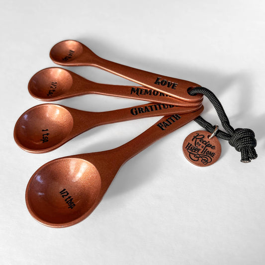 Set of copper measuring spoons with engraved text on a white background
