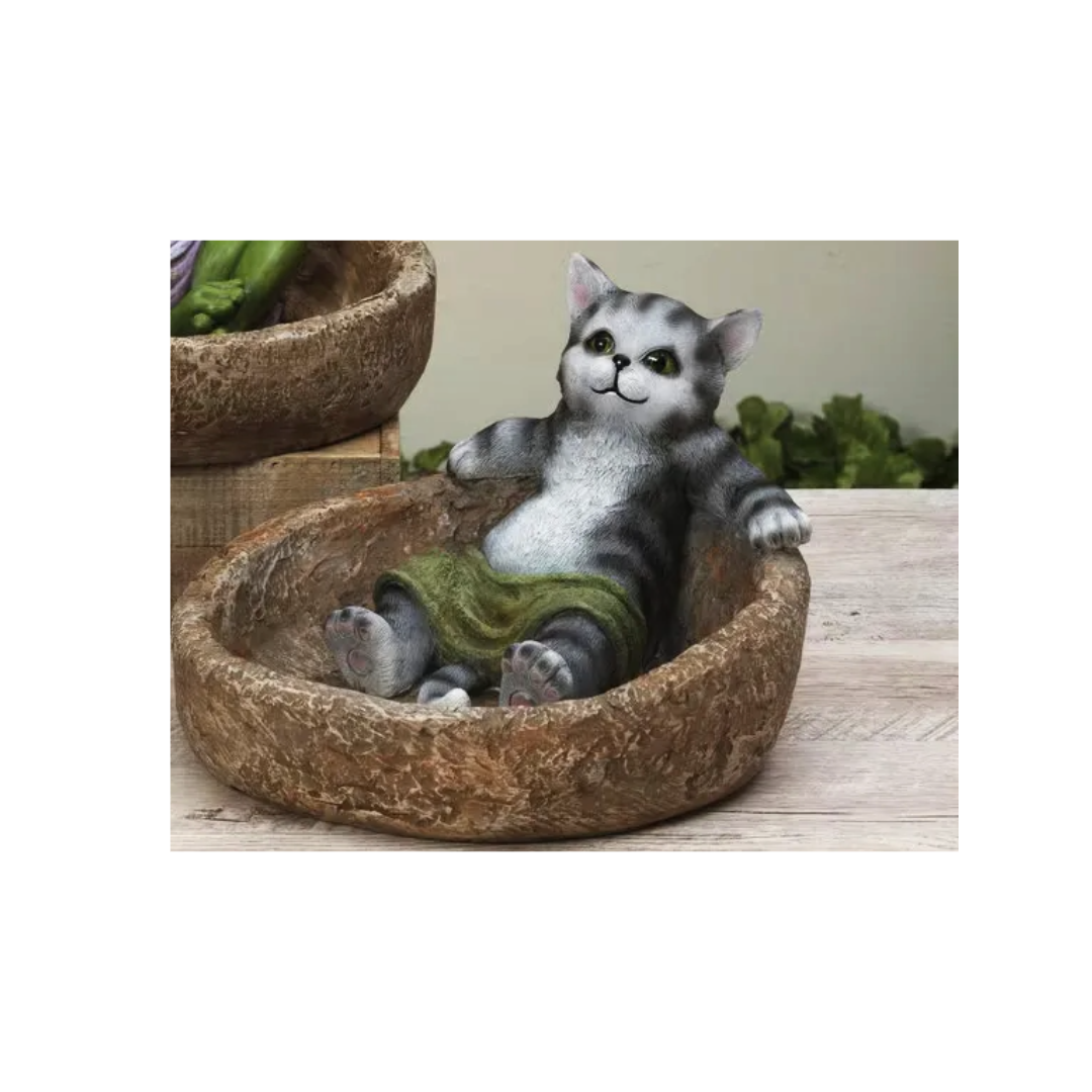 Cat-shaped decorative item in a resin basket on a wooden surface with plants in the background