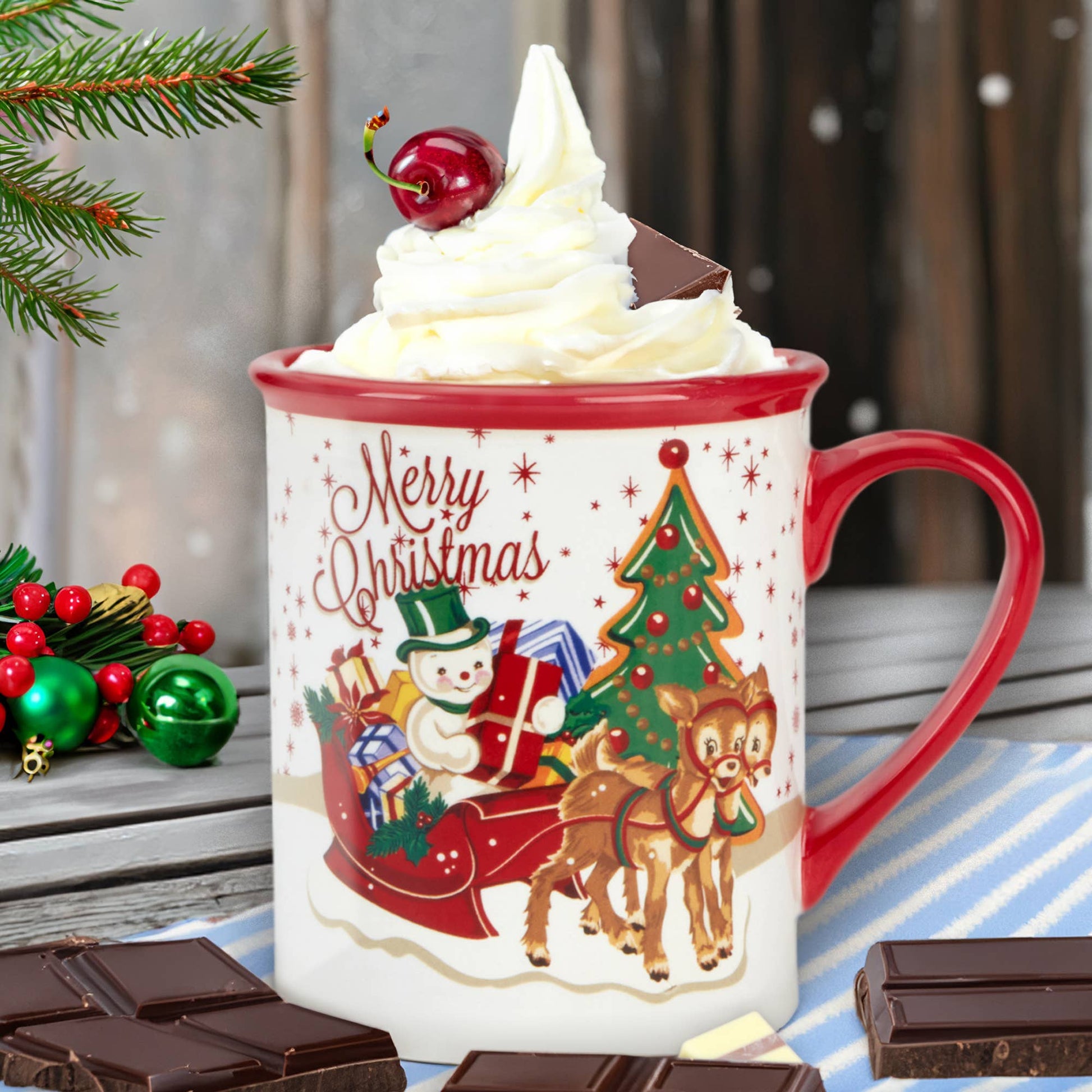Decorative Christmas mug with a snowman and reindeer design, surrounded by chocolate bars and festive decorations.