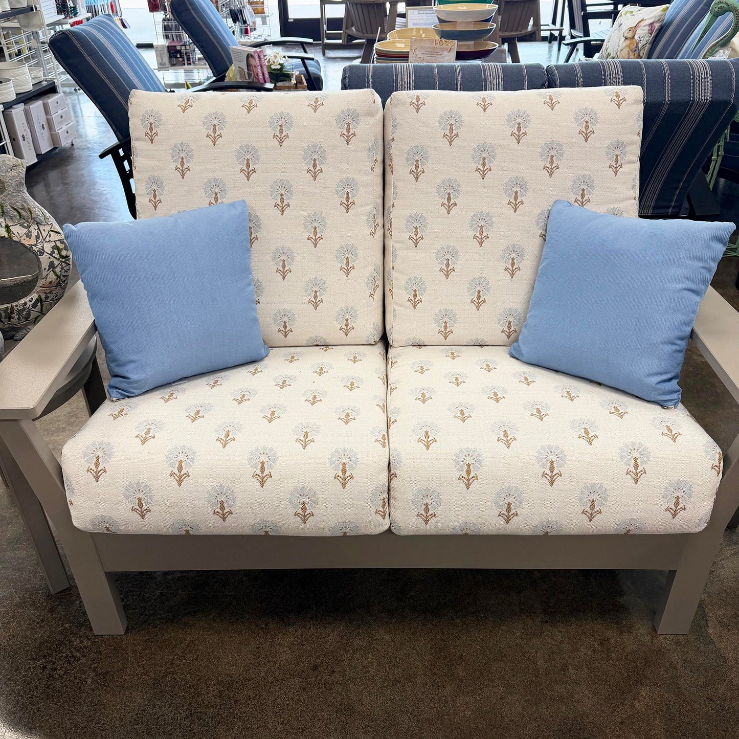 Telescope loveseat with floral pattern and blue cushions in a store setting