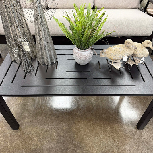 Black polymer table with decorative items including a potted plant, bird figurines.