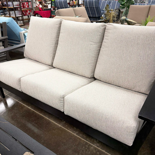 Beige outdoor sofa with black frame in a store setting