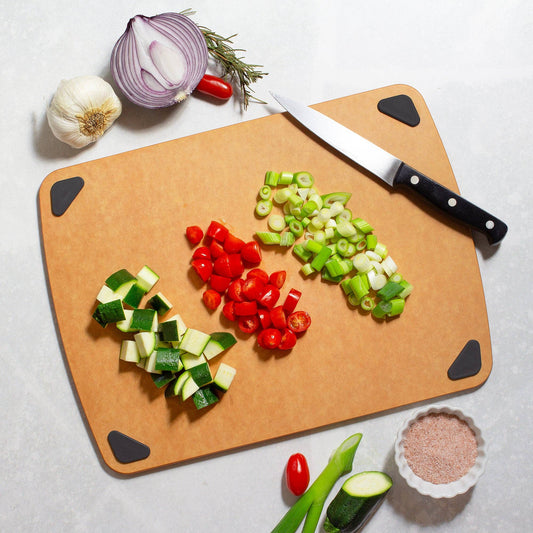 Chopped vegetables on a cutting board with a knife, surrounded by whole vegetables.