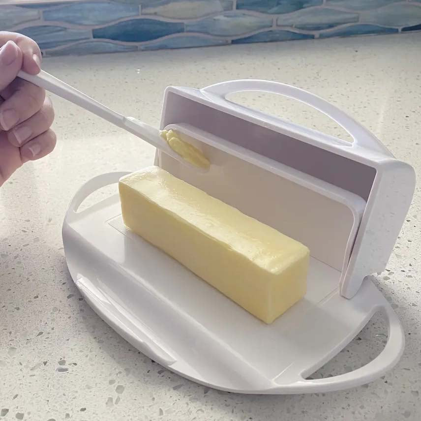 Butter spreader with a stick of butter on a kitchen counter