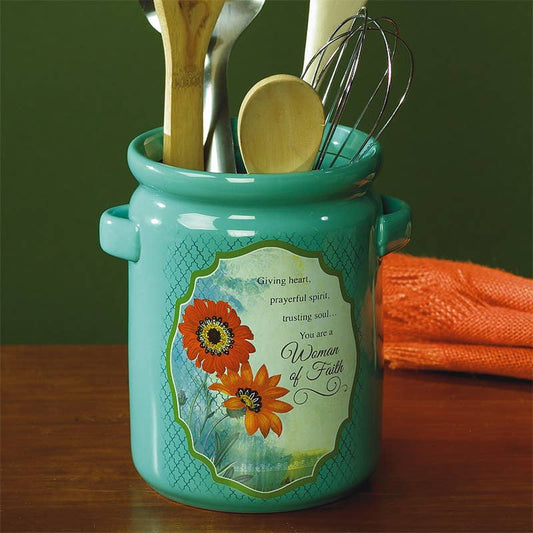 Turquoise kitchen utensil holder with floral design and text on a wooden surface.
