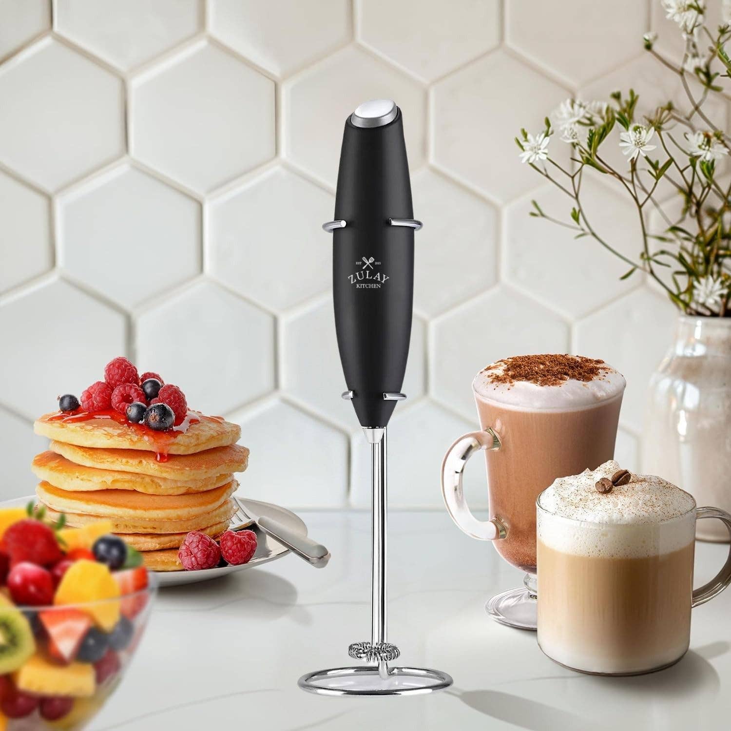 Black hand blender on counter with mugs of hot chocolate