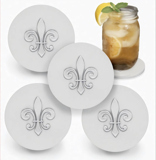 Four round white coasters with fleur-de-lis design on a white background, one coaster with a glass of iced tea.