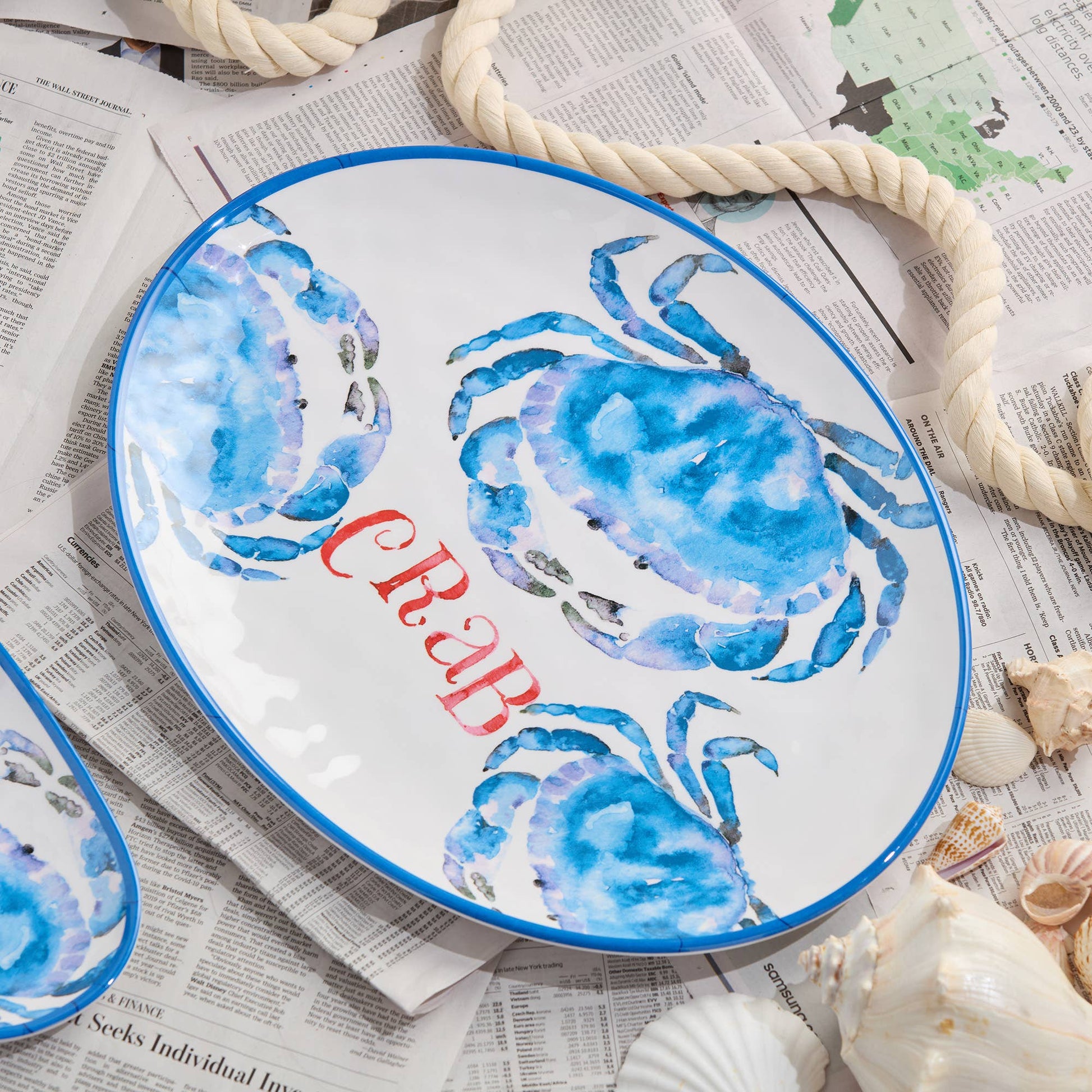 Decorative plate with blue crab design and 'CRAB' text on a newspaper background
