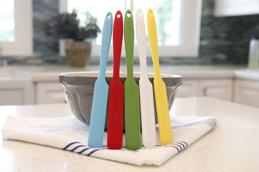 Set of colorful Butteire silicone spatulas in a stand on a kitchen counter.