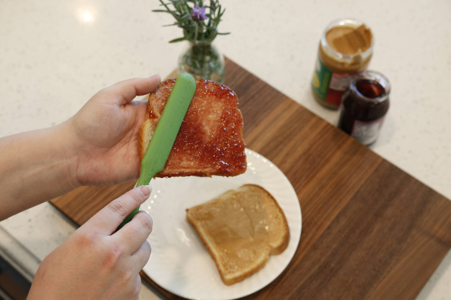 Person spreading jelly on a slice of toast with a green Butterie silicone spatula