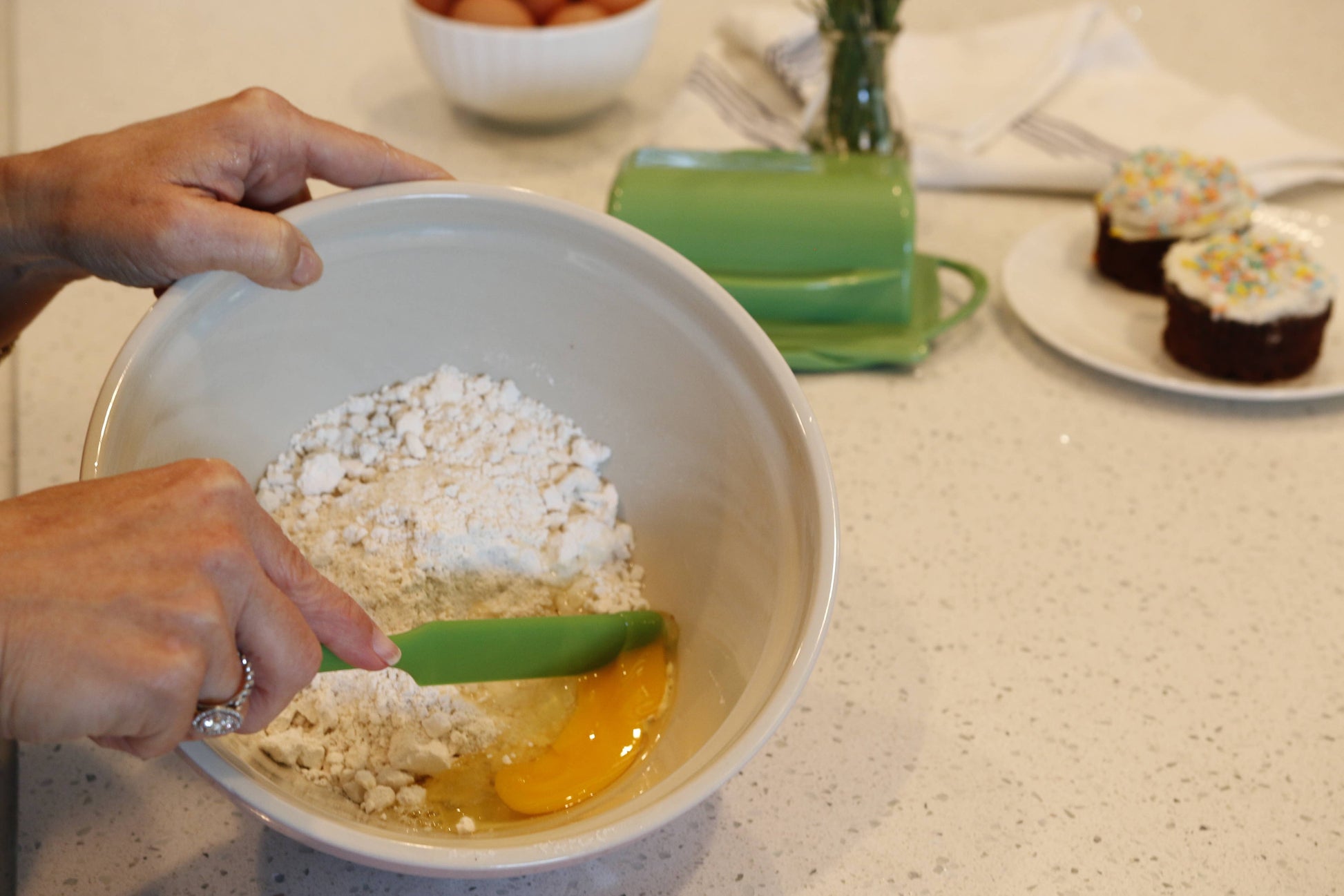 Person mixing ingredients in a bowl using a Butterie silicone spatula in green