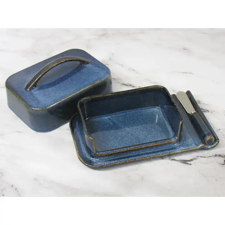 Blue ceramic butter dish with a knife on a marble surface
