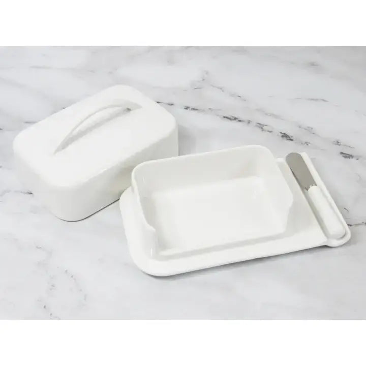 White ceramic butter dish set with lid and knife on a marble surface