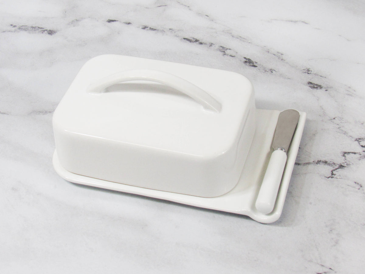 White butter dish with a knife on a marble surface