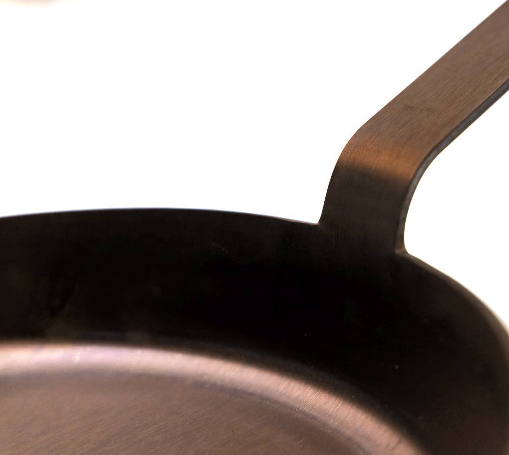 Close-up of a Cast-A-Way Carbon  frying pan with a wooden handle on a white background