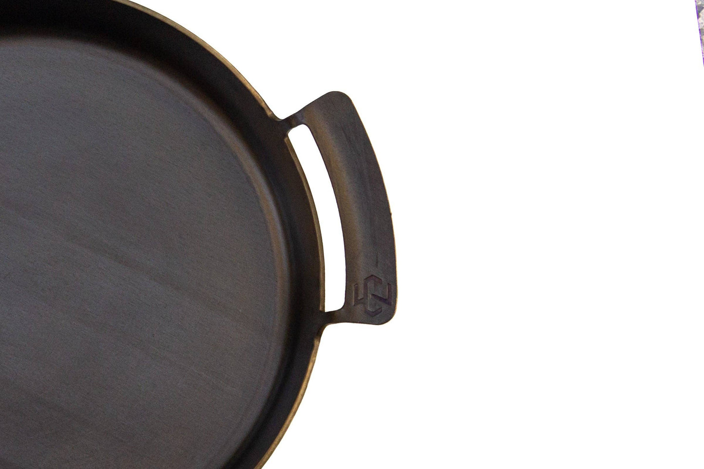 Close-up of a carbon steel skillet with a handle on a white background