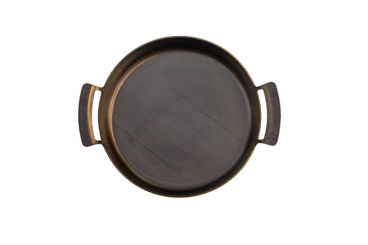 Round carbon steel pan with handles on a white background