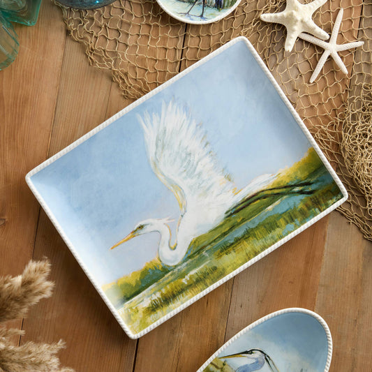 Ceramic platter with a painted scene of a white bird on a wooden surface