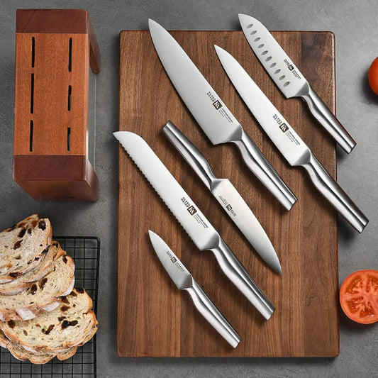 Set of Klaus Meyer Contour knives on a wooden cutting board with bread and tomato on a gray surface