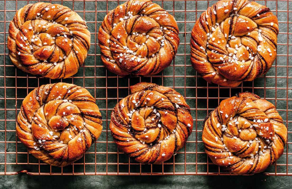 Six braided pastries with a glaze on a cooling rack.