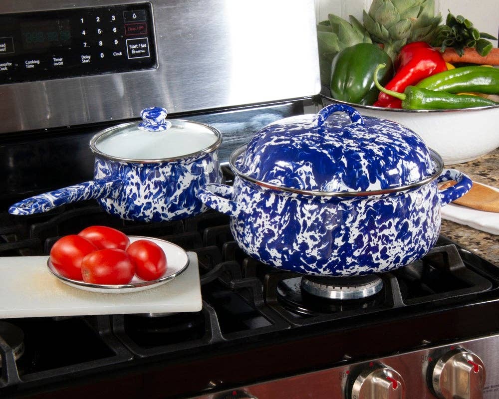 Blue and white enameled pots on a stove with tomatoes and peppers in the background