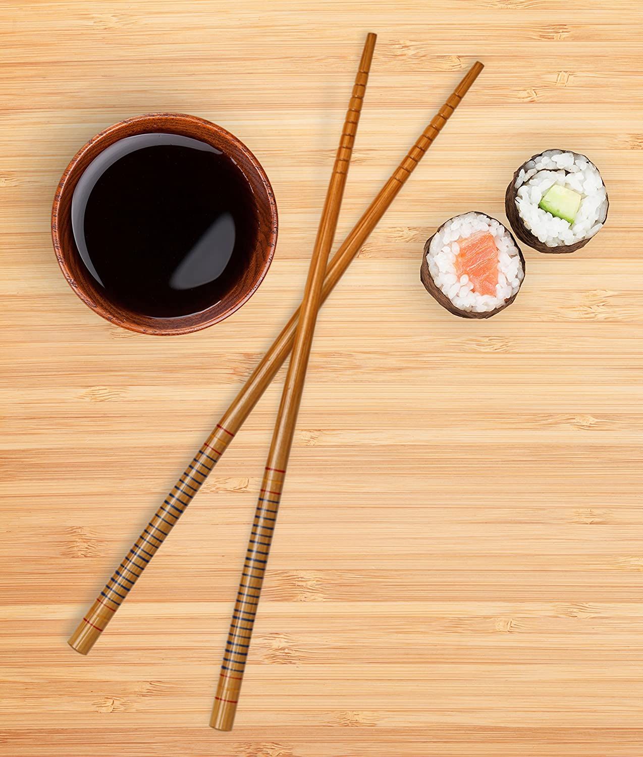 Sushi rolls with soy sauce and chopsticks on a wooden surface