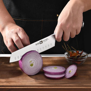 Person slicing a red onion with a Klaus Meyer Stahl Santuko knife on a wooden cutting board.