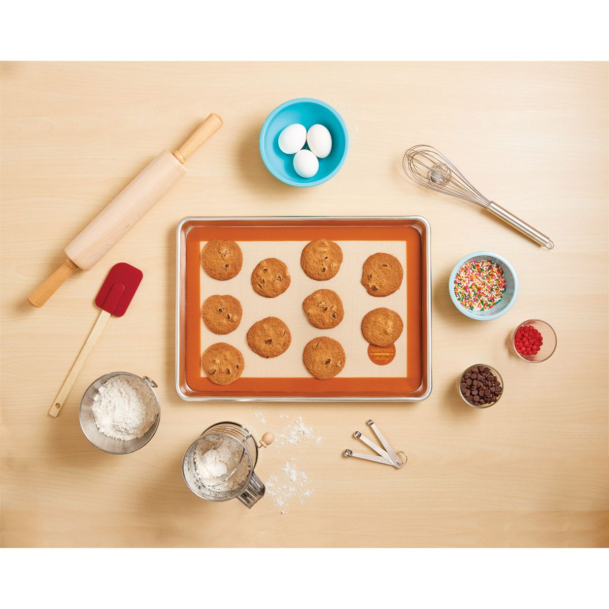 Baking tray with cookies, rolling pin, and various baking utensils on a wooden surface