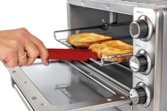 Person using a red toaster tong to remove toast from a toaster oven.