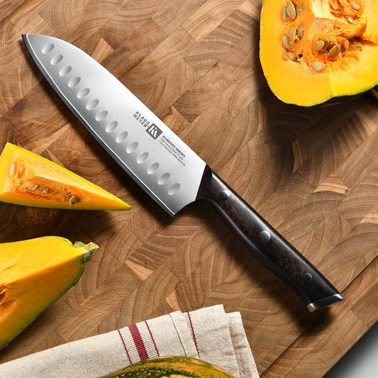 Klaus Meyer Rondure Santoku knife on a wooden cutting board with pumpkin pieces