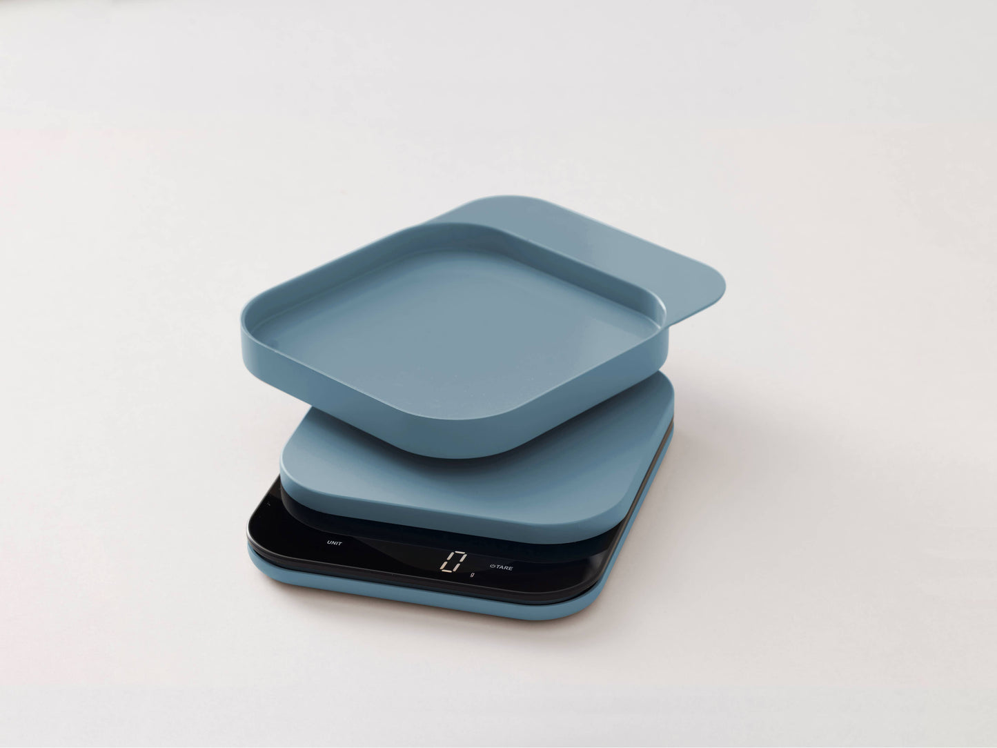 A minimalist digital kitchen scale with a matching square lid, shown in a dusty blue color on a clean white background.